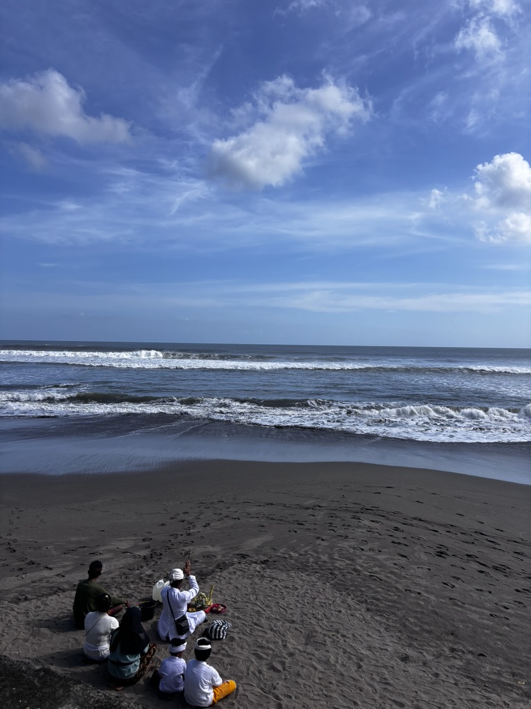A Balinese family gathered in ceremony — flowers, offerings, white cloth, the collective act of saying thank you to the universe