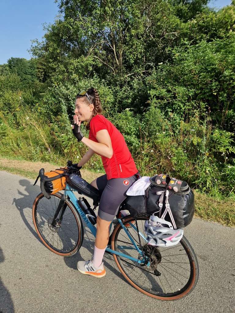Anca cycling with loaded panniers on a road through Serbia, Romania to Croatia bikepacking trip