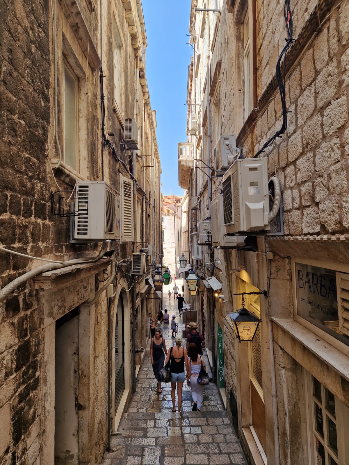 Narrow stone alley with tourists walking through Dubrovnik's old town