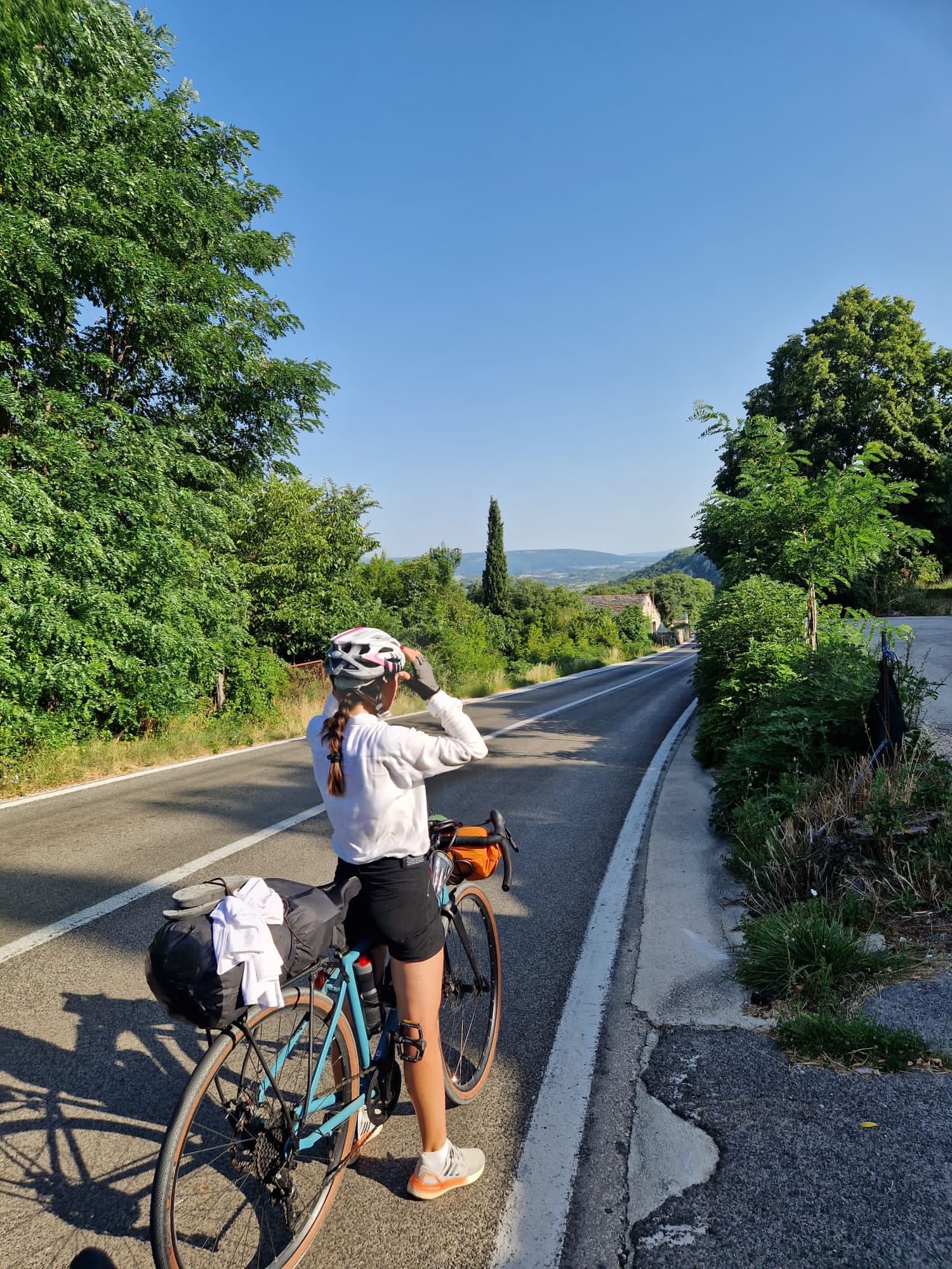 Solo cyclist on a long straight road in early morning light, Romania to Croatia bikepacking trip