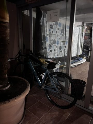 The bike reassembled and leaning against the wall in the hostel, a lived-in bunk room behind it
