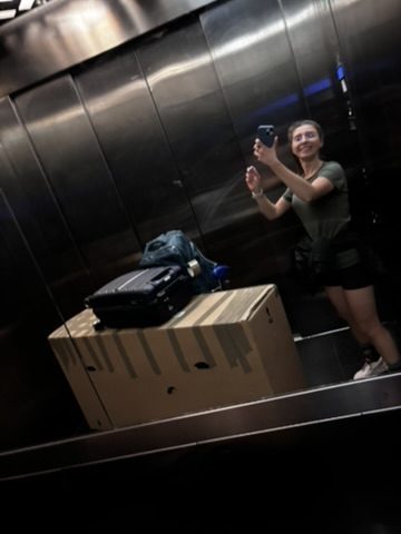 Anca crammed into a small hostel elevator with a bike bag, panniers, and all her luggage — determined face