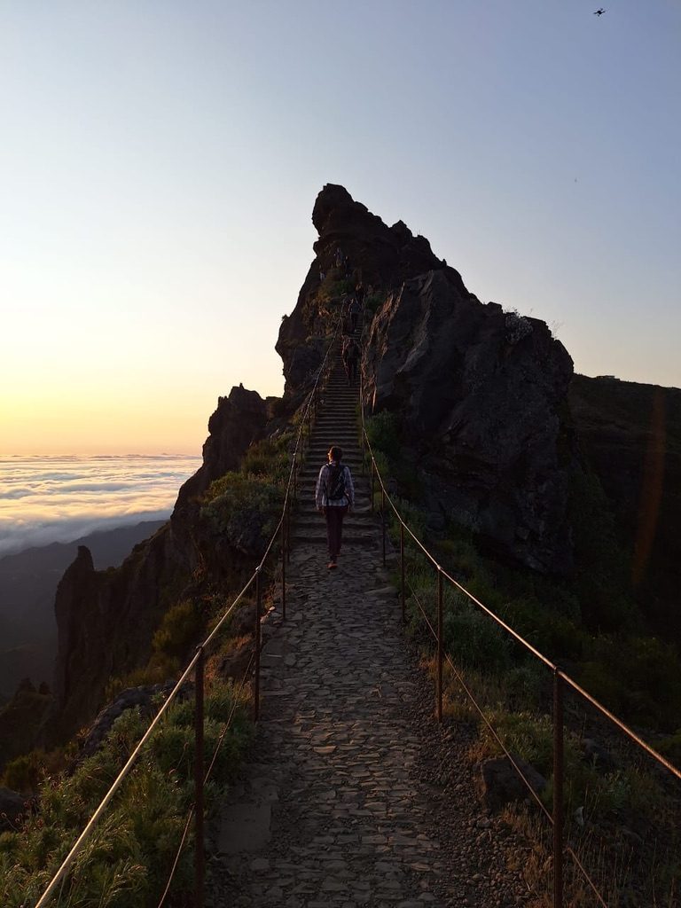 Lone figure climbing Pico Arieiro steps at dawn, above the clouds
