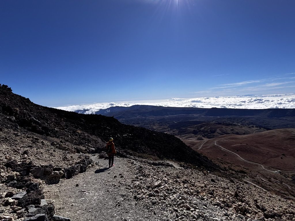 Anca pausing on the El Teide trail at altitude — taking a moment, the vast volcanic landscape around her, listening