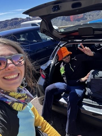 A happy group at the El Teide summit area — hikers who made it, celebrating, the volcanic landscape spread below them