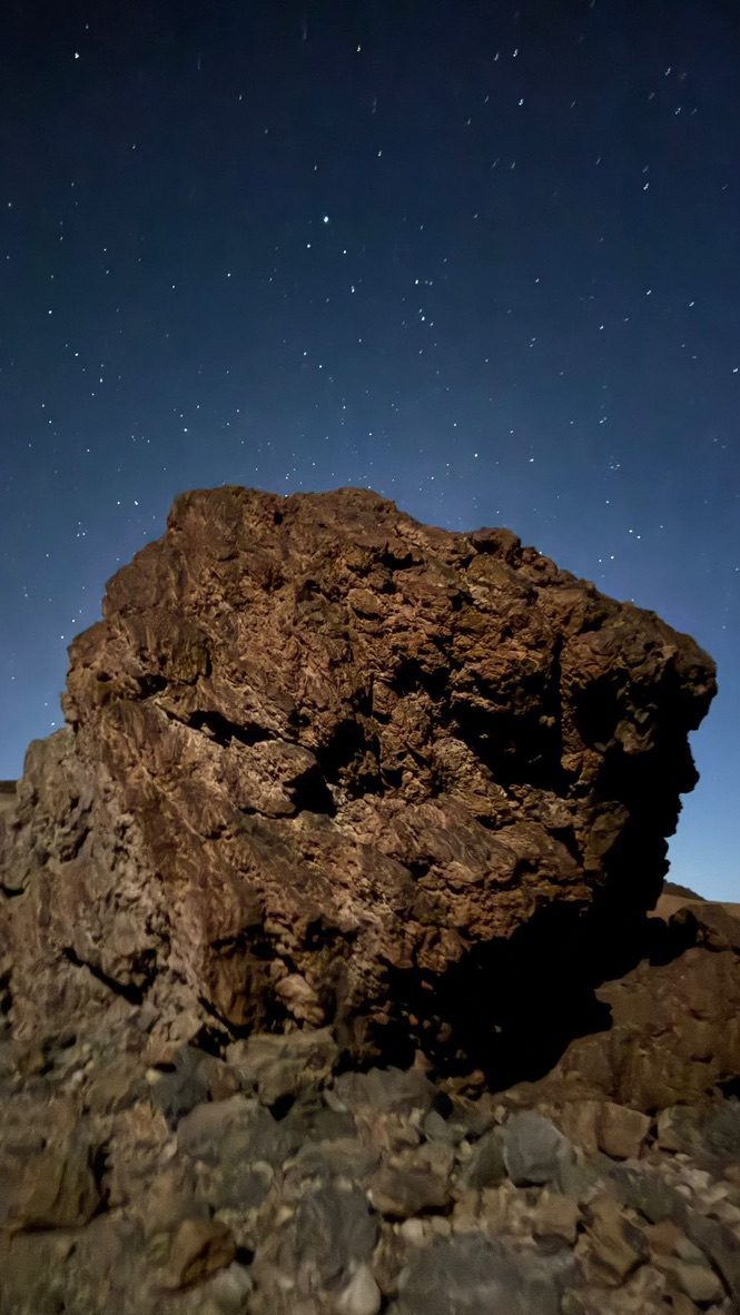 El Teide natural park at night — the dark volcanic landscape lit only by moonlight, the summit visible against stars