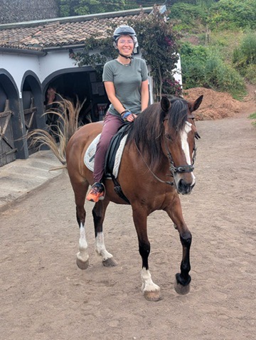 Anca meeting her horse in Sao Miguel — hand extended, the horse's head lowered in the green Azores landscape