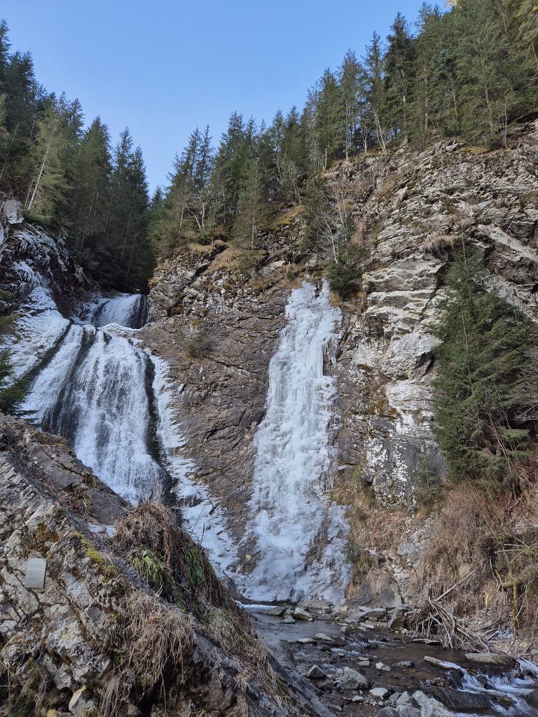 The Bride Waterfall in partial freeze — left side still flowing with water, right side a solid column of ice with icicles