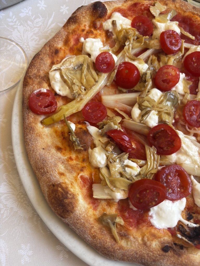 A perfect Neapolitan-style pizza on a table in Caorle — thin crust, charred edges, impossibly good