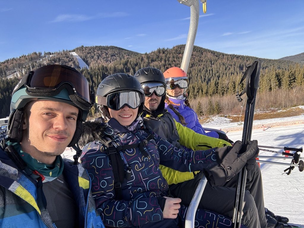 Group of skiers laughing together at the mountain — ski gear, sun on the snow, real happiness