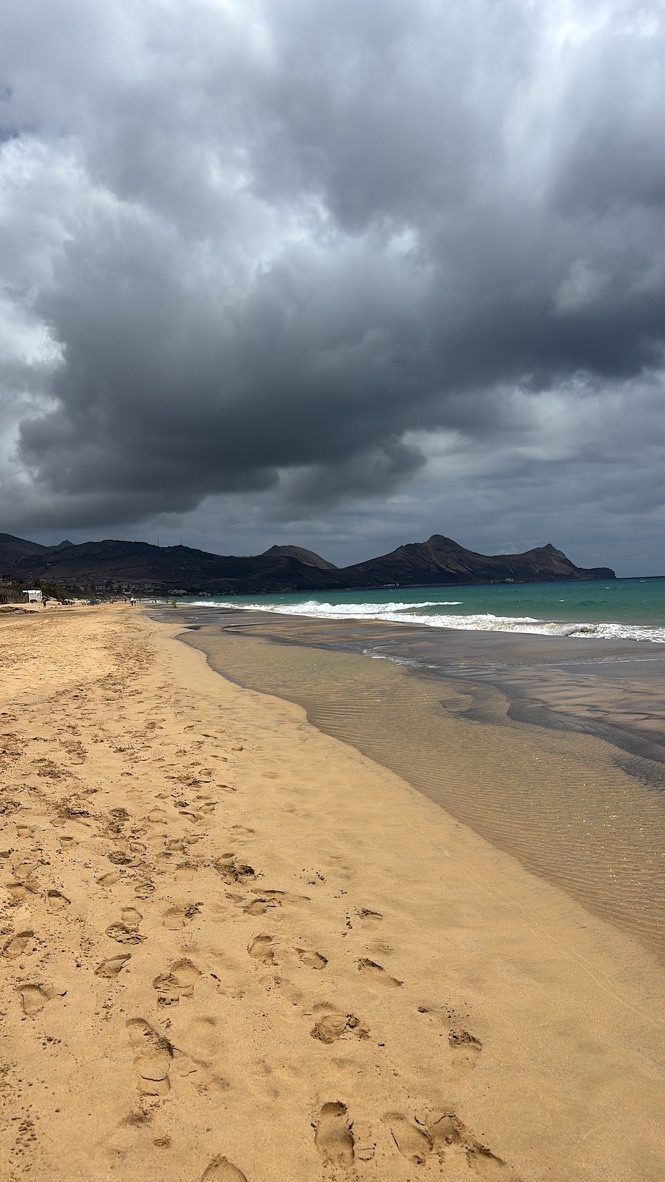 A perfect smaller bay with turquoise water, golden sand and footprints, volcanic black rock headlands either side