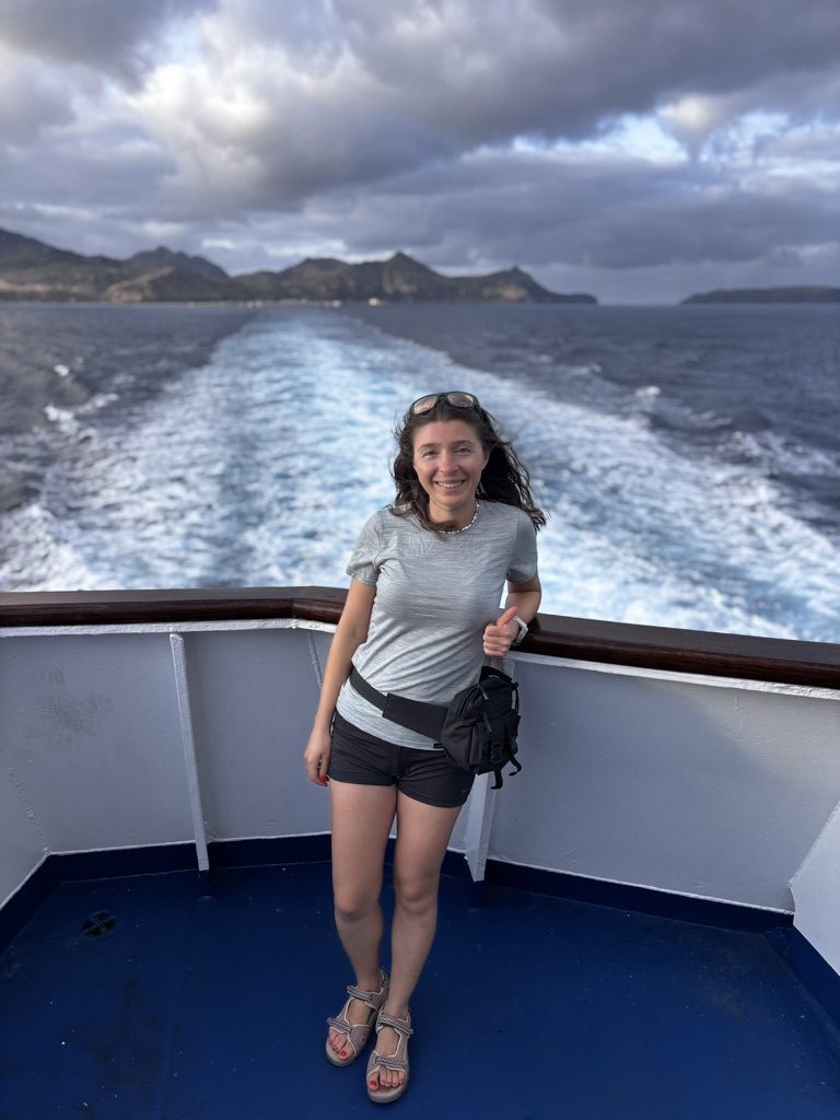 Anca on the rear deck of the Porto Santo ferry, Madeira's mountains receding behind her, choppy Atlantic, wind in her hair