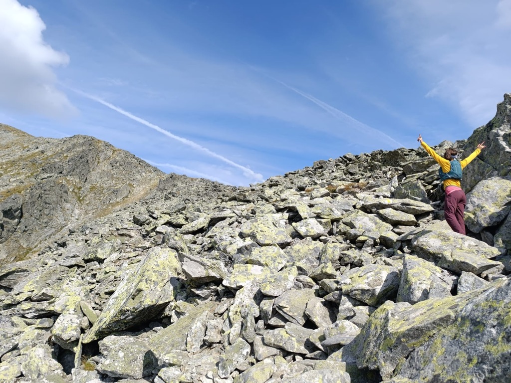 Anca with arms raised on a vast boulder field in the Retezat mountains, Romania