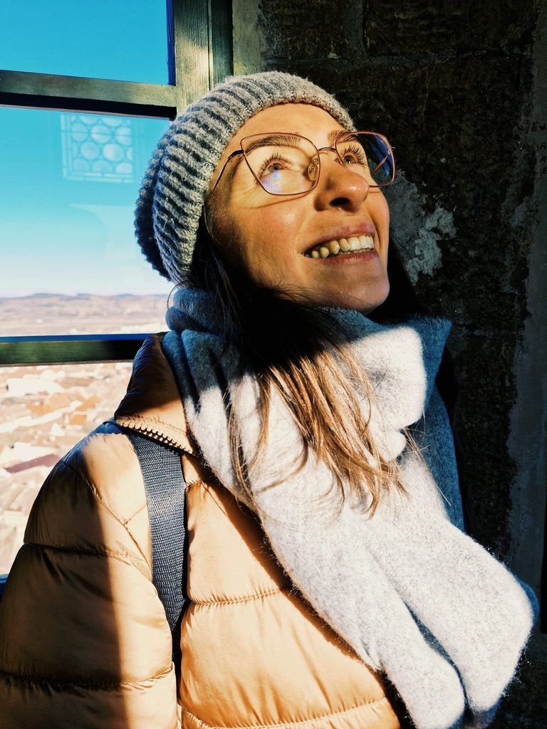 Anca smiling at the top of a medieval tower in Sibiu, blue sky behind
