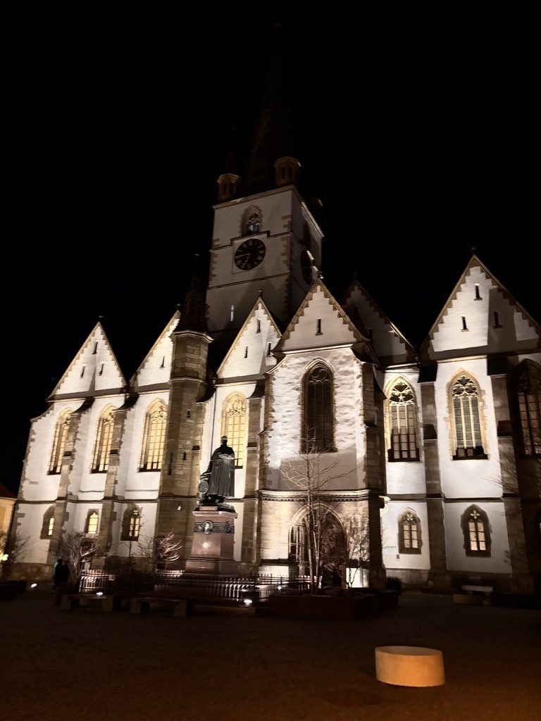 The Evangelical Cathedral of Sibiu lit up at night against a dark blue sky
