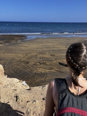 Large text written in the sand on a Tenerife beach: 'sin amor la vida no tiene sentido' — without love, life has no meaning
