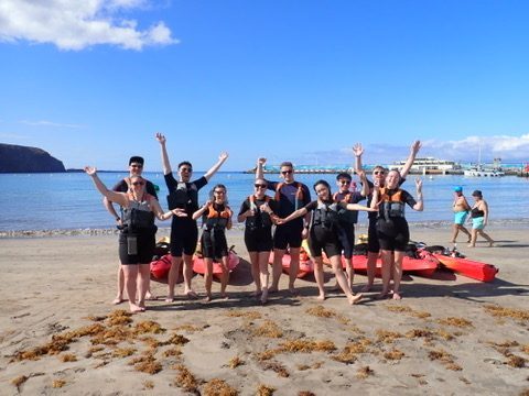 Group of happy kayakers paddling together along the Tenerife coastline, everyone grinning