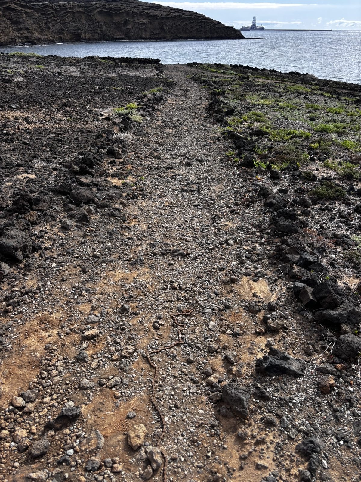 A bicycle chain lying alone on a dusty trail to the beach in Tenerife, no bike in sight