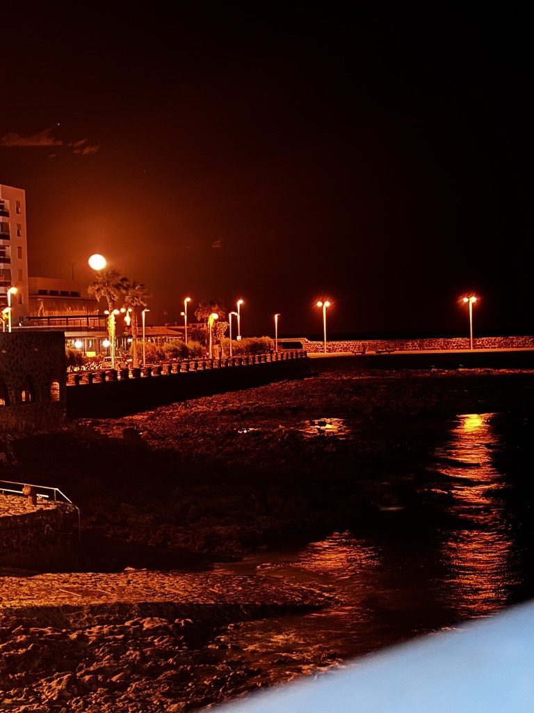 Full moon rising over the Tenerife coast at night, silver light on the dark water