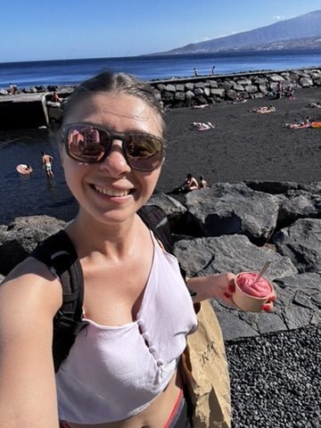 Anca on the beach in Tenerife with an ice cream, post-work golden hour, completely satisfied expression