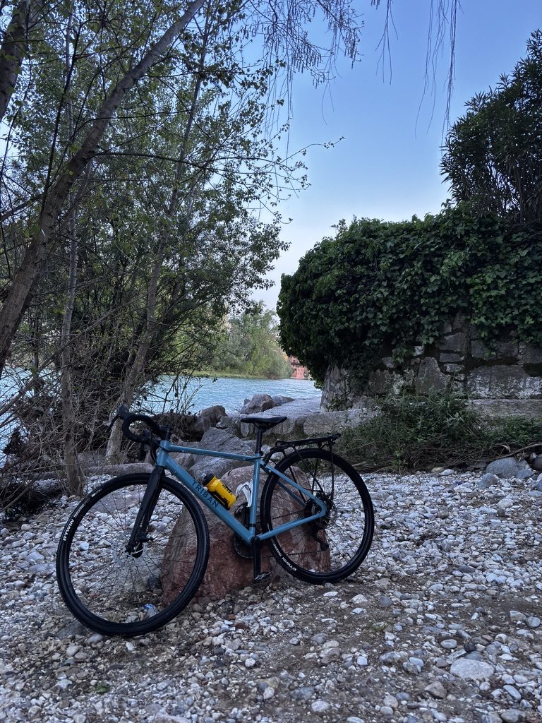 Cleaning the bike in a river after the Veneto gravel ride — bike in the water, everything washed off