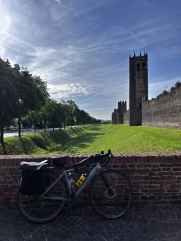 Anca cycling free in the Veneto countryside, arms open, gravel road ahead