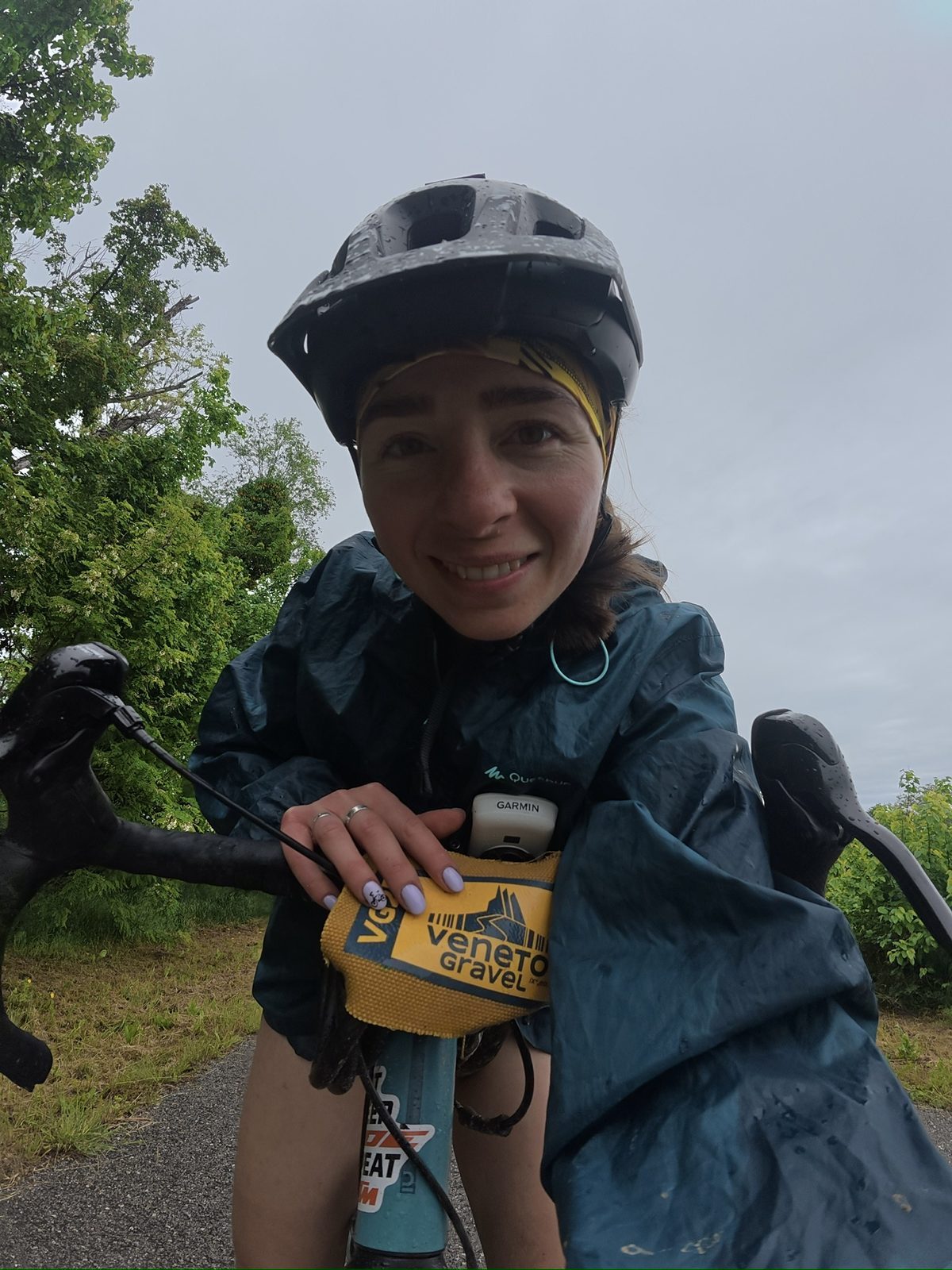 Anca pushing through rain and discomfort on the Veneto Gravel — nails-in-the-ground determination, bike in hand