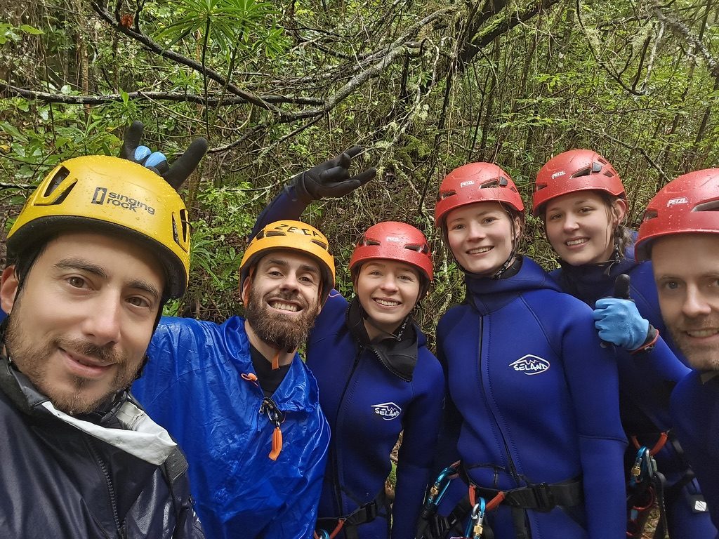 Group of friends at the waterfall rappelling spot in Madeira, geared up and ready to go