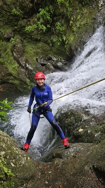 Anca geared up at the waterfall, focused expression, ropes and harness on, ready to descend