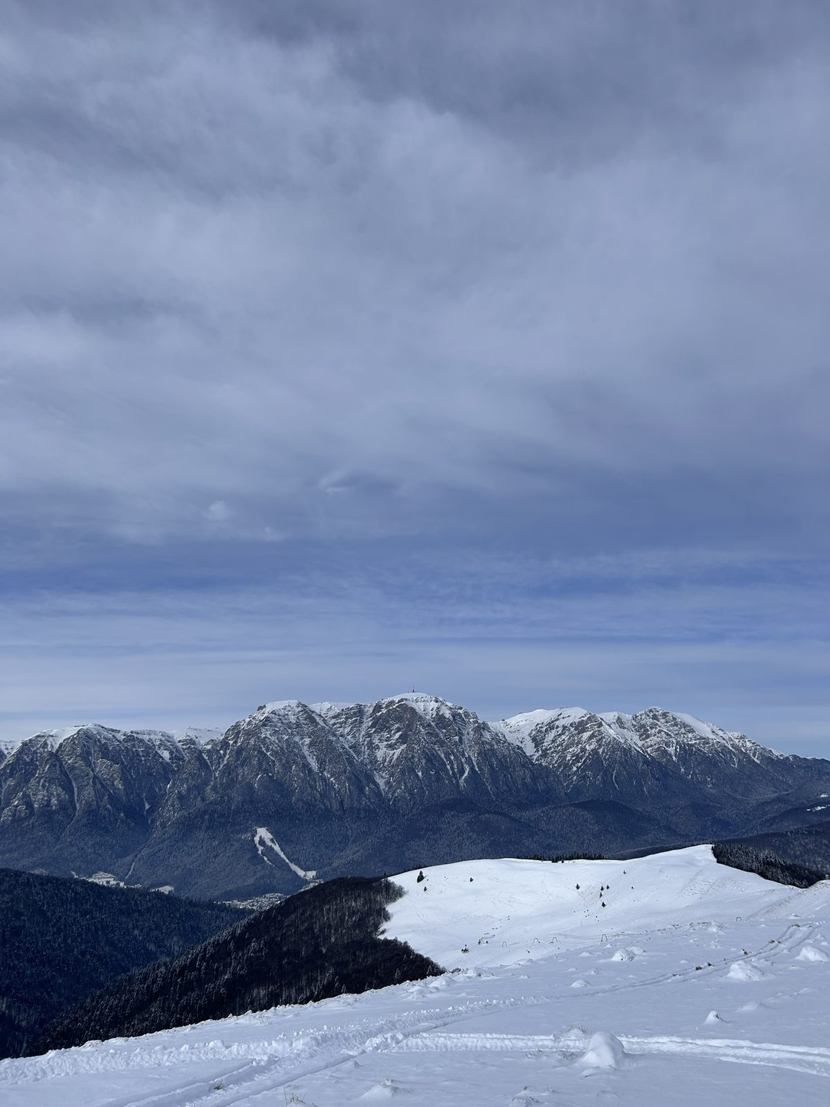 Anca hiking through deep snow in the Romanian mountains, pine forest and white slopes all around